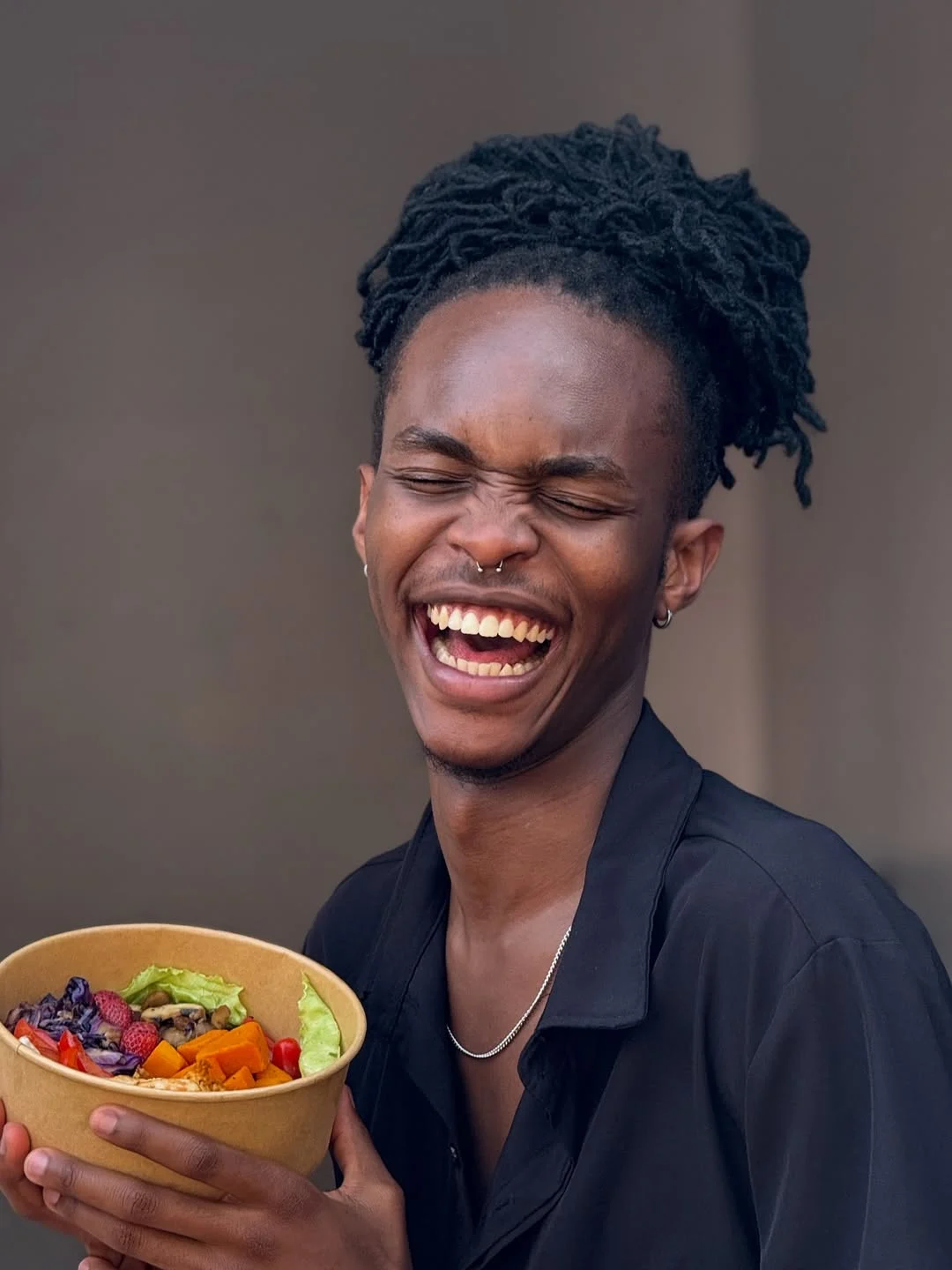 A smiling person holding a colourful JooSmoo bowl